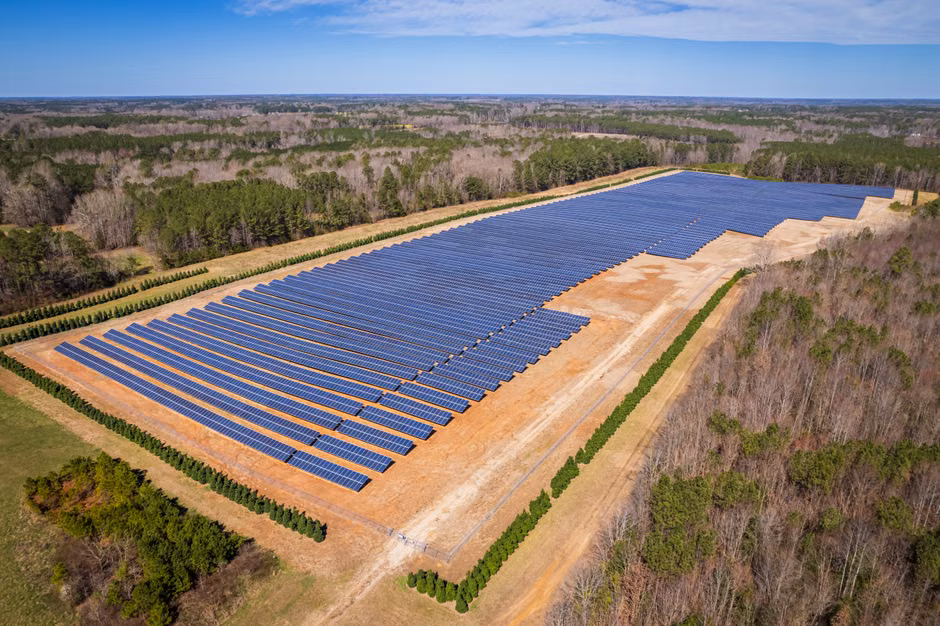 Reducing Carbon Footprint: Energy and Emissions Management for Thermal Spas Aerial drone shot of a large solar panel farm in a rural area surrounded by forests in North Carolina.